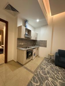 a kitchen with a stove and a couch in a room at Diwan Al Nuzha Serviced Apartments in Mecca