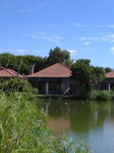 a house next to a body of water at Pecanwood Estate Cosy home 3 bedrooms with pool in Hartbeespoort