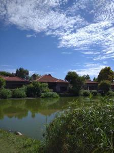 a pond in a yard with houses and a cloudy sky at Pecanwood Estate Cosy home 3 bedrooms with pool in Hartbeespoort +46 photos