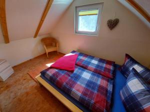 a bedroom with a bed and a window in a attic at Ferienhaus zur Dorfbachklamm in Altendorf