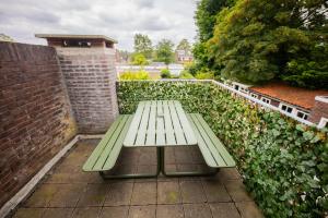 a green bench sitting on a patio next to a brick wall at Amazing 50m2 Two-Bedroom Apartment - TS307A in Eindhoven