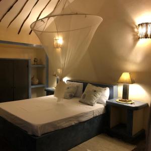 a bedroom with a bed with a chandelier above it at Toubana Lodge in Ngaparou