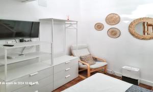 een witte kamer met een tv en een stoel bij Studio at Barbate 300 m away from the beach with furnished terrace and wifi in Barbate