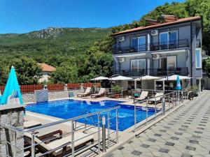 a building with a swimming pool with chairs and umbrellas at Villa Mimi in Peštani