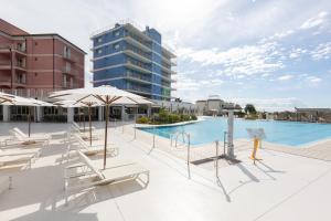 洛阿諾的住宿－Ai Pozzi Village Resort & SPA，一座带椅子和遮阳伞的游泳池位于一座建筑旁边