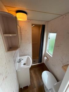 ein kleines Bad mit einem Waschbecken und einem WC in der Unterkunft SummerCampMielno Domki Holenderskie in Mielno