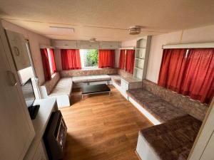 梅尔诺SummerCamp Domki Holenderskie Centrum Mielno 200m do Morza的一间空客厅,配有红色窗帘和沙发