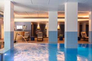 Ai Pozzi Village Resort & SPA في لوانو: مسبح في بهو فندق فيه اعمدة