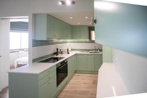 una cucina con armadi verdi e ripiani bianchi di Palmove Luxurious Beachfront Apt a Larnaka