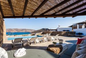 a patio with chairs and a pool with a view at Mykonos Panormos Villas in Mykonos