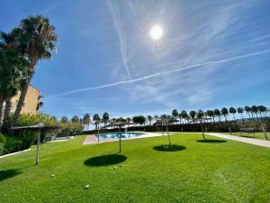 un parc avec une piscine et des palmiers dans l'établissement Elimann ground floor seaside by HLCLUB Agency, à Vilanova i la Geltrú