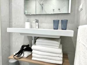 a bathroom with a sink and a pile of towels at Apartamento Calas in Noja +29 photos