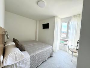 a white bedroom with a bed and a window at Apartamento Calas in Noja