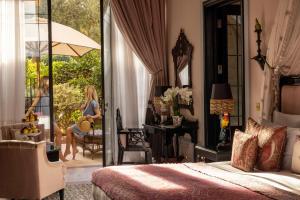 - une chambre avec une femme assise sur une chaise sur une terrasse dans l'établissement Palais Ronsard Relais & Chateaux, à Marrakech