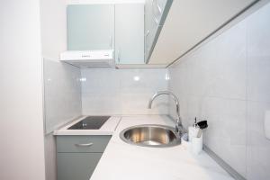 a kitchen with a stainless steel sink and white cabinets at Apartment Kjara in Herceg-Novi