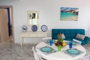 a living room with a table and a blue couch at Ammos Beach Apartment in Skaleta