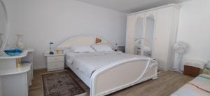 a white bedroom with a bed and a dresser at More in Crikvenica +16 photos