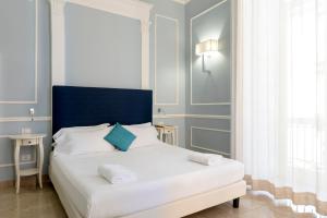 a white bed with a blue headboard in a room at Napolit'amo Hotel Principe in Naples