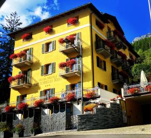 un bâtiment jaune avec des boîtes de fleurs sur les balcons dans l'établissement Hotel Meublè Sertorelli Reit, à Bormio