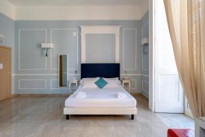 a bedroom with a white bed and a mirror at Napolit'amo Hotel Principe in Naples