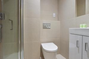 uma casa de banho com um chuveiro, um WC e um lavatório. em Regents Serviced Apartments by StayPrime em Londres