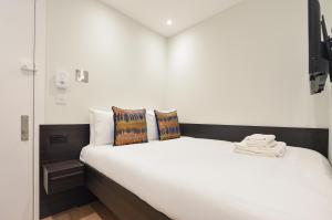 um quarto com uma cama branca com almofadas em Regents Serviced Apartments by StayPrime em Londres