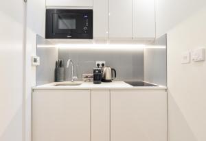 uma cozinha com um lavatório e um micro-ondas em Regents Serviced Apartments by StayPrime em Londres