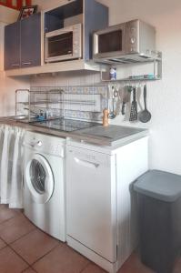uma cozinha com uma máquina de lavar roupa e um micro-ondas em Maison de 2 chambres avec piscine partagee jardin clos et wifi a Eyguieres em Eyguières