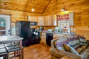 a living room with a couch and a kitchen with wooden walls at Cabin In The Smokeys in Gatlinburg