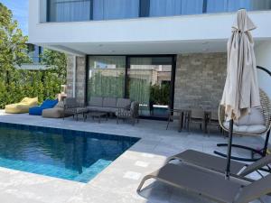 a pool with chairs and an umbrella next to a building at Villa 7 SanPietro in Draç
