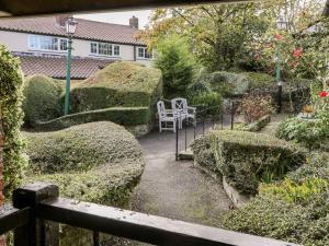 a garden with hedges and a white chair in it at Ivy in Filey
