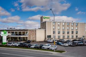 een groot gebouw met auto's geparkeerd op een parkeerplaats bij Holiday Inn Sudbury, an IHG Hotel in Sudbury