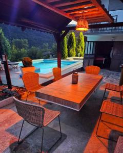 une table et des chaises en bois sur une terrasse avec une piscine dans l'établissement Vikendica sa bazenom, à Višegrad
