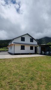 a white house with black windows and a yard at Villa Piton Textor in La Plaine des Palmistes