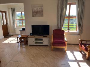 a living room with a tv and a chair at Cloonkee Cottage in Crossmolina