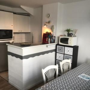 eine Küche mit einer Theke mit Stühlen und einer Mikrowelle in der Unterkunft BELLE DUNE Village Vacances face à l'Aquaclub de FORT MAHON in Fort-Mahon-Plage