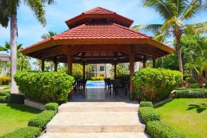 a pavilion with a table and chairs in a garden at White Sands Punta Cana - Pool-Jacuzzi in Punta Cana