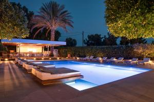 a swimming pool with lounge chairs around it at night at Danae Hotel in Egina
