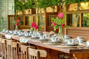 una larga mesa de madera con sillas y flores rosas en Albergo Diffuso Locanda Senio en Palazzuolo sul Senio