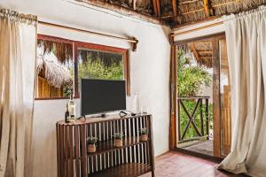 a living room with a tv and a window at Xhule Tulum in Tulum