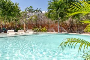 a swimming pool with two chairs and palm trees at Xhule Tulum in Tulum