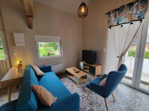 a living room with a blue couch and a tv at La Mésange bleue in Ognes