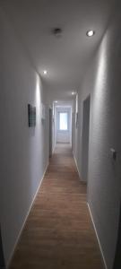a hallway of an empty room with white walls and wood floors at Ferienwohnung für bis zu 10 Personen in Koetz 