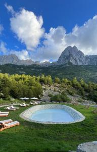 a swimming pool in a field with mountains in the background at North Alpine Villas in Bogë