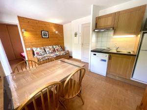 kuchnia i salon ze stołem i kanapą w obiekcie Appartement cosy au pied des pistes avec piscine, balcon et parking privé - FR-1-505-170 w mieście Flumet