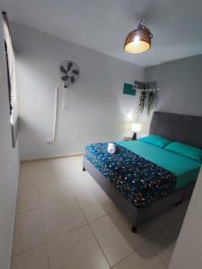 1 dormitorio con 1 cama con sábanas azules y ventilador en Apartamento de verano cerca al parque del café en La Tebaida