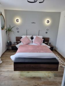 une chambre avec un grand lit avec des oreillers roses dans l'établissement Les Appart du Sillon, à Pleubian