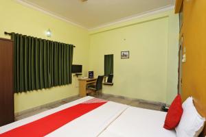 een slaapkamer met een bed en een bureau met een computer bij Hotel O Regency Guest house Near TCS Gitobitan in Calcutta