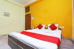 een slaapkamer met een groot bed met gele muren en rode kussens bij Hotel O Regency Guest house Near TCS Gitobitan in Calcutta