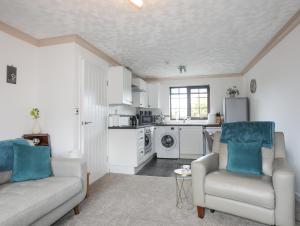 uma sala de estar com duas cadeiras e uma cozinha em Cae Ffynnon em Gaerwen